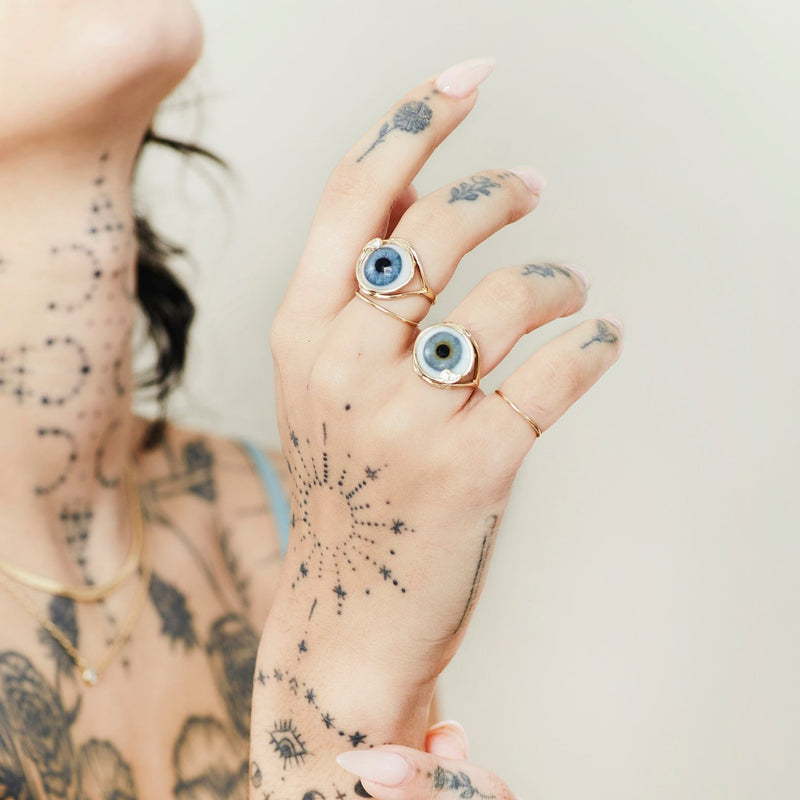 2 gold glass eye skeleton rings on tattooed model